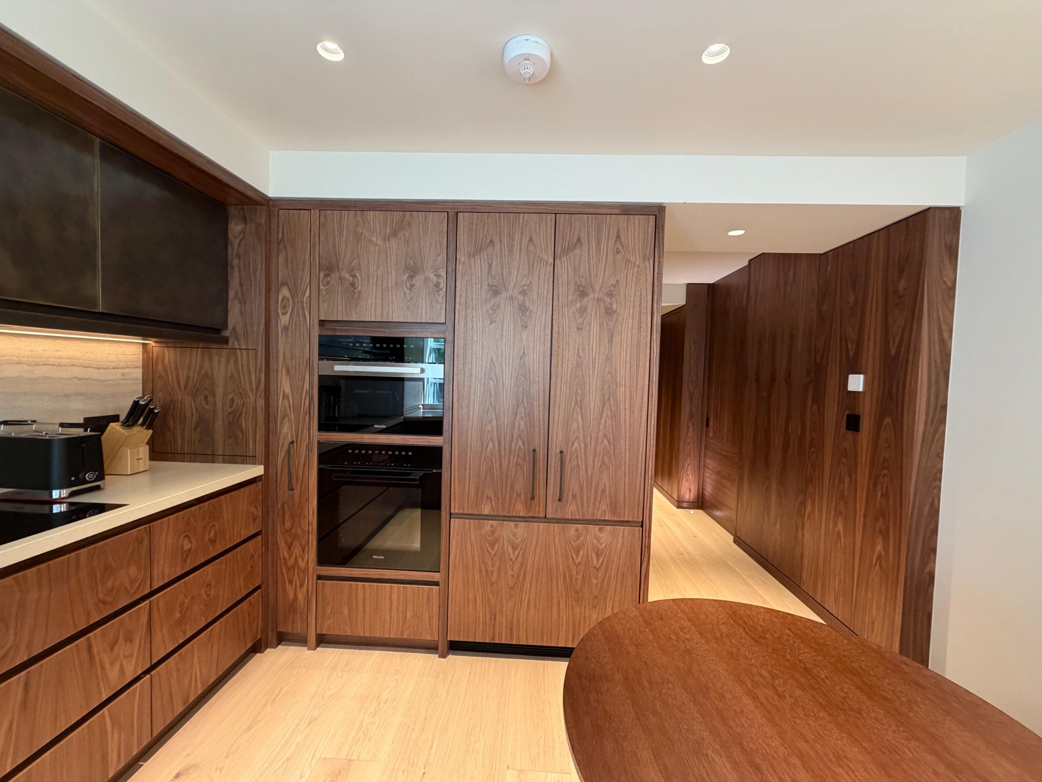 Kitchen with tall appliance cabinetry and timber table